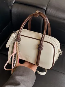 Chic cream mini barrel pillow bag with contrasting brown handles and decorative charm