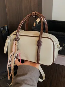 Chic cream mini pillow bag with brown handles and an adjustable crossbody strap