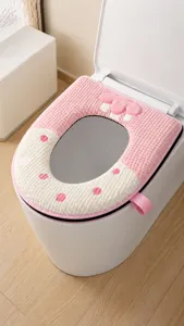 Dettaglio ravvicinato della maniglia in fettuccia rosa e della morbida trama del copriwater
