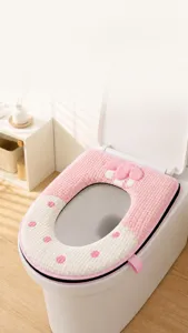 Dettaglio di un copriwater spesso in peluche rosa e bianco con un grazioso fiocco e pois