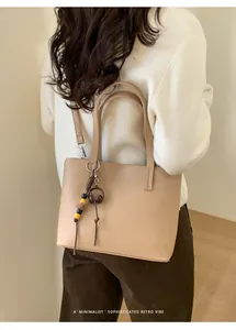 Vista dettagliata di una borsa tote beige retrò minimalista con ciondolo