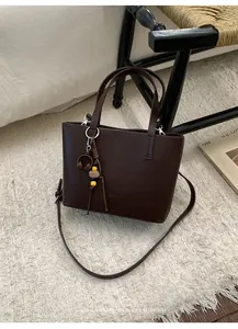 Borsa tote minimalista in pelle marrone scuro con ciondolo retrò su tappeto testurizzato
