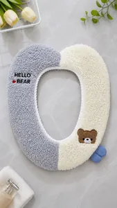 Close-up of plush cartoon toilet seat cover with heart bear embroidery in gray and white.