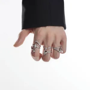 Detalle de anillos punk de estrellas irregulares usados en la mano con manga negra