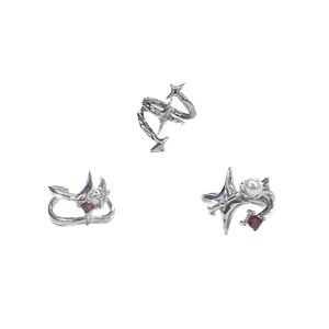 Primer plano de tres anillos punk irregulares con estrellas, perlas y gemas rojas