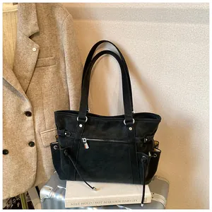 Bolso tote negro vintage de gran capacidad presentado sobre una maleta plateada