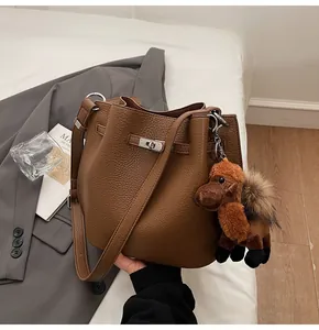 Close-up of retro brown pebbled leather bucket bag with a cute plush horse charm