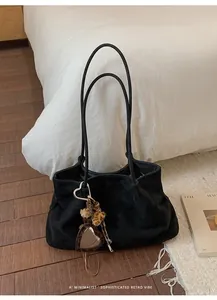 Detailed view of a large black suede tote bag featuring a retro heart leopard charm