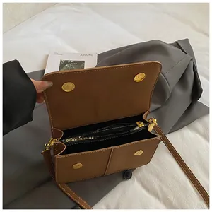 Interior view showing compartments and zipper of a minimalist brown square bag.