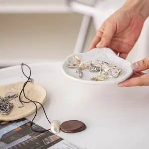 Primer plano de una elegante bandeja de cerámica para joyas con pulseras y anillos