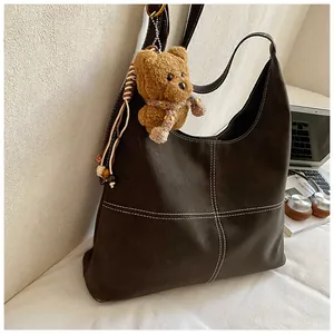 Detalle de bolso tote vintage marrón con adorno de osito y costuras en contraste