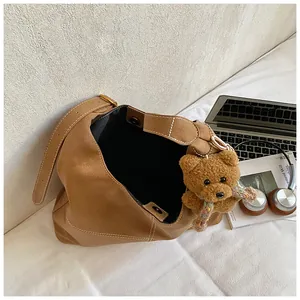 Detalle de bolso hobo marrón retro con un lindo colgante de peluche de osito
