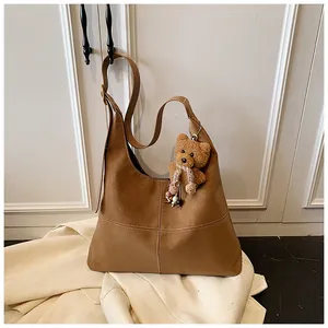 Primer plano de bolso hobo retro de ante marrón con un bonito colgante de oso
