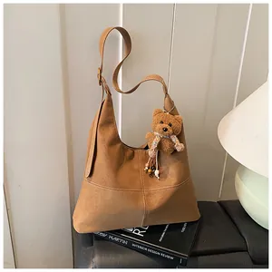 Bolso de hombro vintage de ante marrón con un lindo amuleto de oso de peluche en un libro