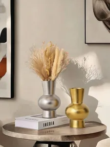 Vases en céramique texturés or et argent avec herbe de la pampa sur une table basse.