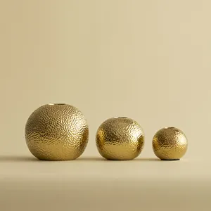 Detail van de gehamerde textuur op luxe gouden bolvormige keramische vazen in drie maten