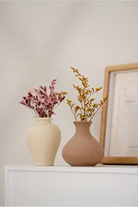Minimalist matte ceramic vases with dried flowers on a white mantel for home decor.