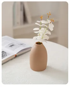 Detail view of an elegant beige ceramic vase on a white lace tablecloth for home decor