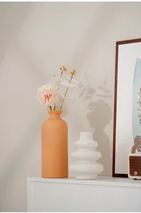 Modern minimalist ceramic vases displayed in a warm home setting with art and flowers