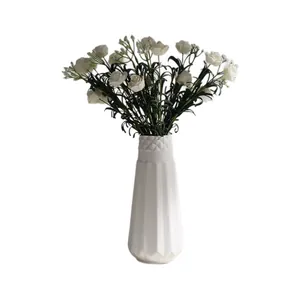 Minimalist white ceramic vase with artificial small roses for elegant home decoration.