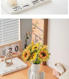Detail view of white ceramic angel vase with sunflowers on a cozy home office desk setup