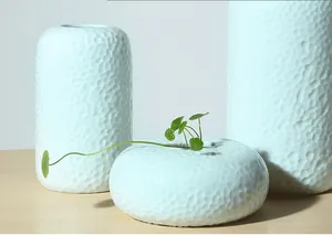 Detailopname van minimalistische lichtblauwe keramische vazen met handgemaakte hamertextuur.