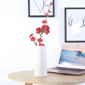 Modern minimalist white ceramic flower vase with red plum blossoms for home decoration