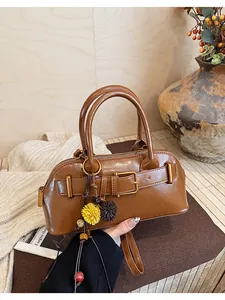 Primo piano di una borsa vintage marrone con fibbia e ciondoli a forma di fiore