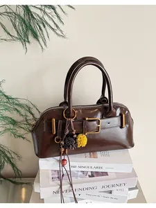 Dettaglio di una borsa a mano vintage in ecopelle marrone con ciondoli decorativi