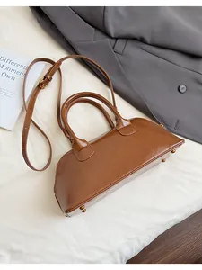 Dettaglio della borsa a conchiglia marrone vintage con finitura in ecopelle lucida.