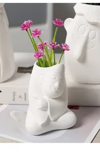 Macro view of white ceramic humanoid vase with playful expression and pink flowers
