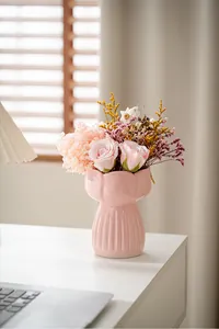 Detail view of a pink ceramic vase with a petal-shaped rim and elegant ribbed texture