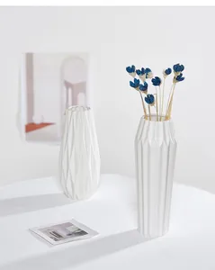 Detalle de primer plano de jarrones de cerámica blanca minimalistas con flores azules