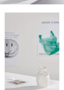 Detailed macro view of a minimalist white textured ceramic vase with dual ring handles