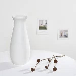 Vase en céramique blanche minimaliste posé sur une table avec un décor de branche