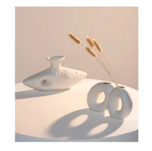 Artistic detail of organic white ceramic vases with dried grass under soft warm lighting