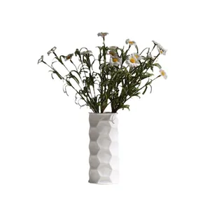 Modern white ceramic vase with hexagonal honeycomb texture and artificial daisies