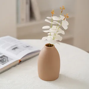 Minimalist matte beige ceramic vase with white artificial flowers for home decor