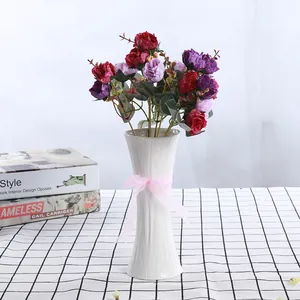 Vase élégant en céramique blanche avec ruban rose et bouquet de roses artificielles