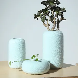 Set van 3 minimalistische lichtblauwe keramische vazen met gehamerde textuur op tafel