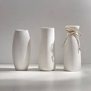 Elegant set of three minimalist white ceramic vases with natural sunlight and soft shadows