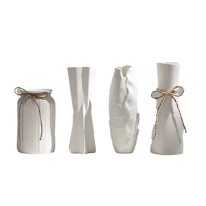 Set of four modern minimalist white ceramic vases for elegant home tabletop decoration.