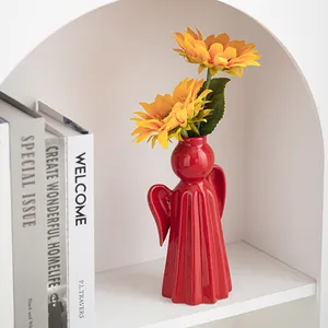 Modern red angel shaped ceramic vase with sunflowers in a stylish home decor setting