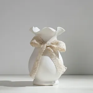 Vase moderne en céramique blanche avec bord ondulé et nœud en dentelle décoratif