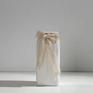 Vase à fleurs minimaliste en céramique blanche avec un ruban de dentelle délicat décoratif