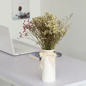 Minimalist white ceramic vase with lace bow and dried flowers for desk decor
