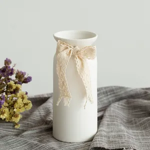 Minimalist white ceramic vase decorated with a delicate beige lace bow
