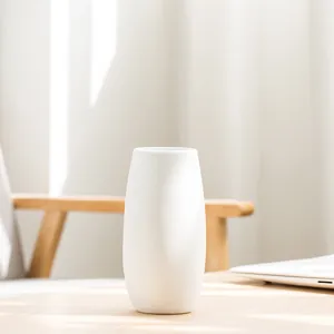 Minimalist white ceramic flower vase for home decor on a wooden table under natural light