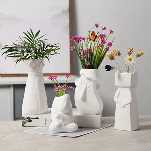 Set of creative white ceramic vases with cute cartoon face designs for home decor.