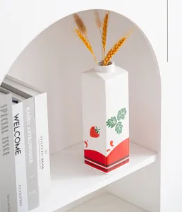 Detailweergave van het aardbeienpatroon op de witte keramische melkpak-vormige vaas